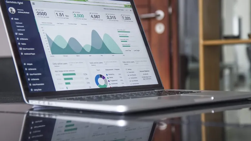 Analytics dashboard open on a desktop monitor in a dark office, charts showing utilization and revenue trending in opposite directions